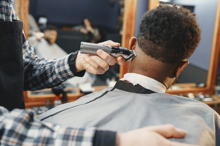Barbero perfilando la nuca con máquina frente al espejo