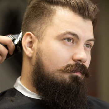Barbero recortando el contorno de barba y patilla