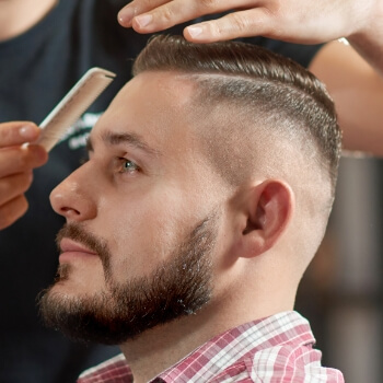 Barbero definiendo un fade con peine y máquina