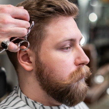 Barbero texturizando el cabello con tijera de entresacar
